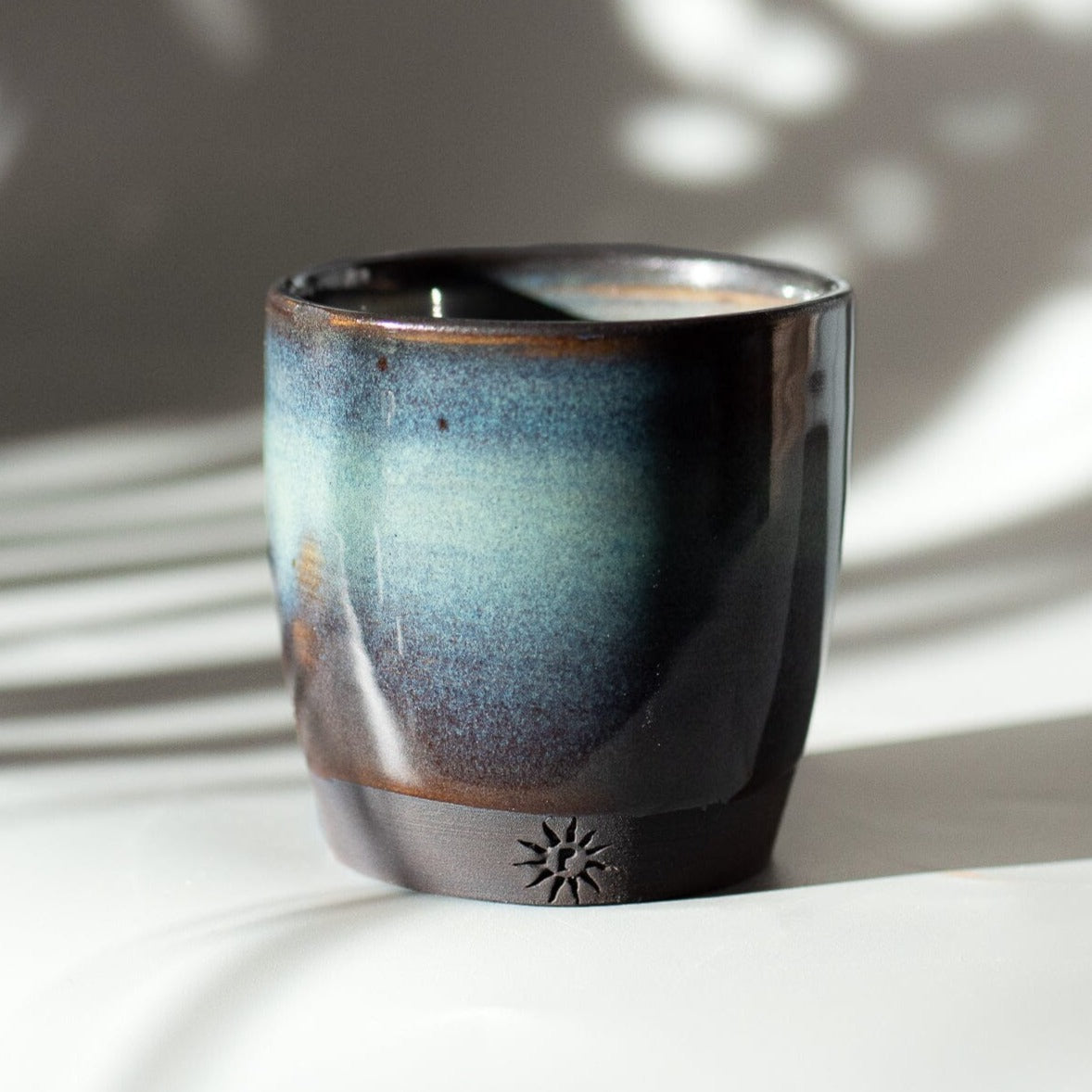 Turquoise espresso cup hand thrown in black clay. Floating blue glaze.