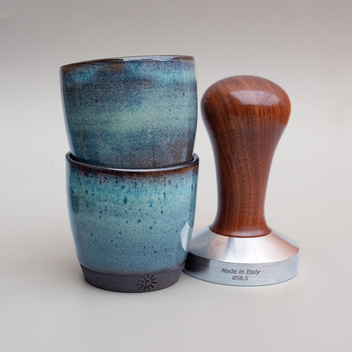 Espresso cups, next to coffee tamper for scale