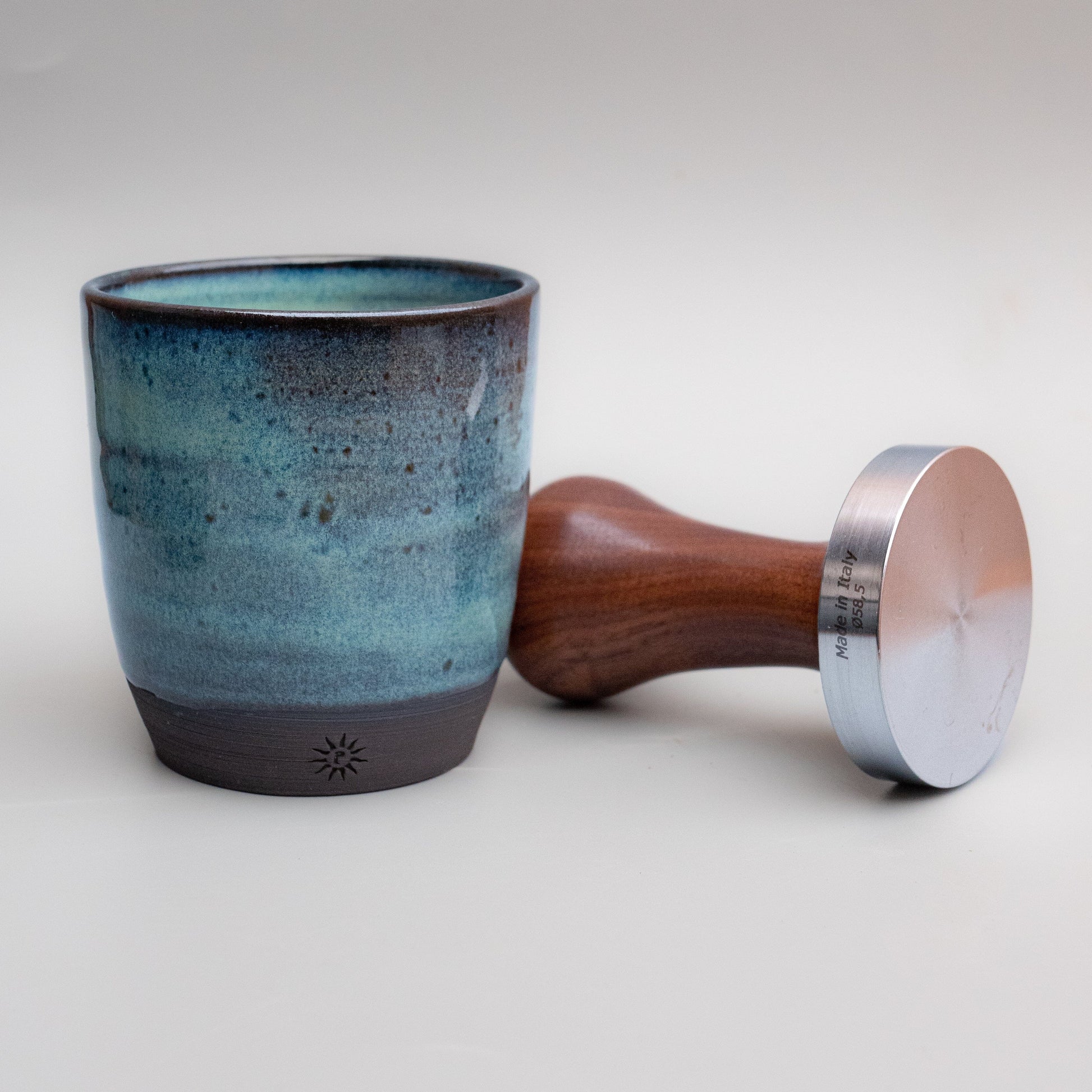 Pottery tumbler. Turquoise with coffee tamp for scale